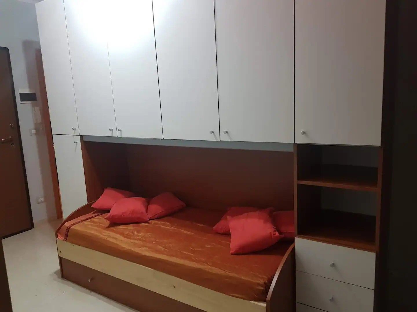 Una camera da letto con un letto, armadi contenitori e una cassettiera in legno.