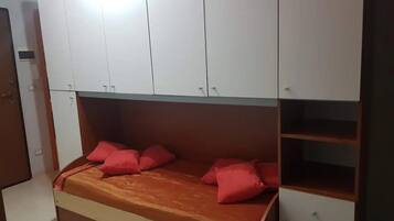 Una camera da letto con un letto, armadi contenitori e una cassettiera in legno.