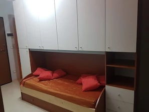 A bedroom with a bed, storage cabinets, and a wooden dresser.
