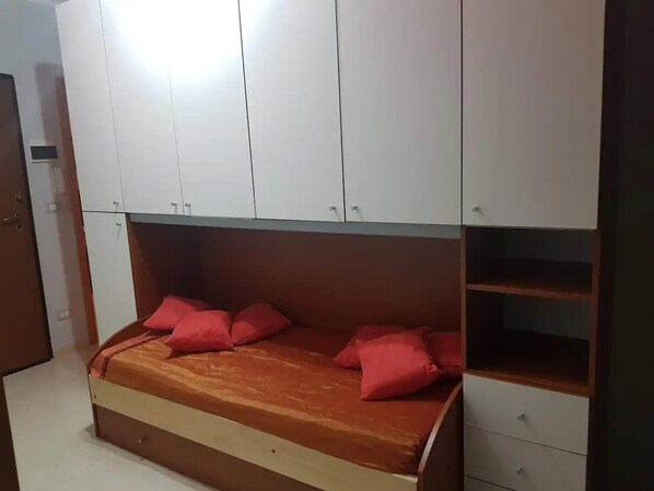 A bedroom with a bed, storage cabinets, and a wooden dresser.