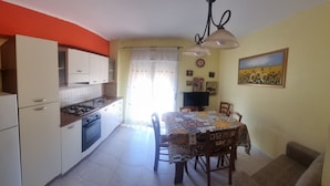 A compact kitchen with a dining area, a refrigerator, a stove, and a table with chairs. - Apartment 'Casa in Complesso Sonia' with Private Terrace (Santa Teresa di Riva)