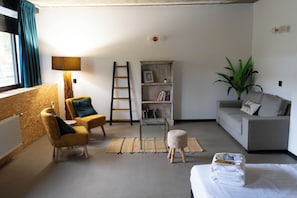 A living room with a sofa, armchairs, a coffee table, a bookshelf, a ladder, a plant, and a radiator. - Large Room in Rijswijk (Rijswijk)