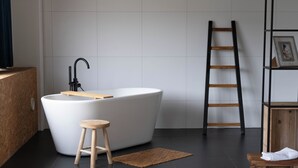 A modern bathroom with a freestanding bathtub, a wooden stool, a black tiled floor, and a wooden ladder. - Large Room in Rijswijk (Rijswijk)