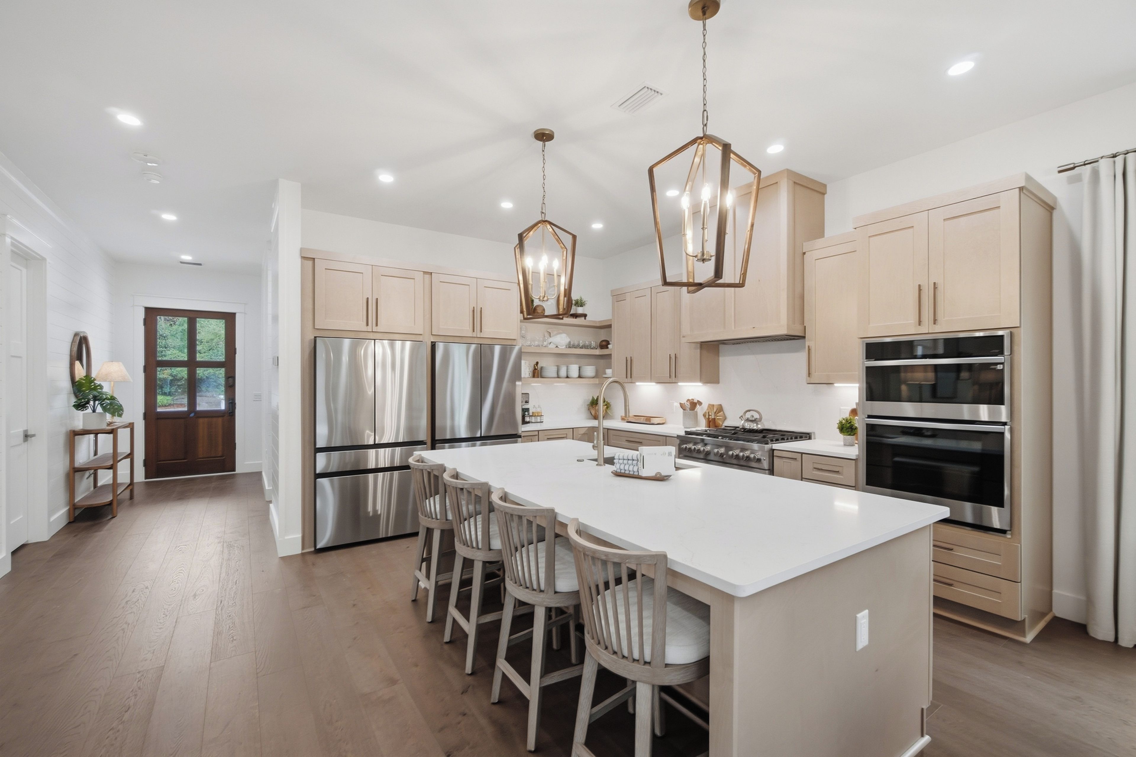 A modern kitchen with stainless steel appliances, a central island with bar stools, and pendant lighting.