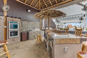 Eine Küche mit Steinrückwand, Holzstühlen und einem Strohdach.