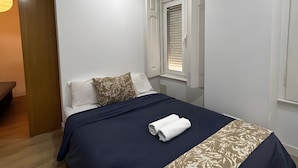 A bedroom with a bed, a window with blinds, a door, and a light fixture. - Holiday Home 'Lisboa Guest House' with Wi-Fi (Lisboa)
