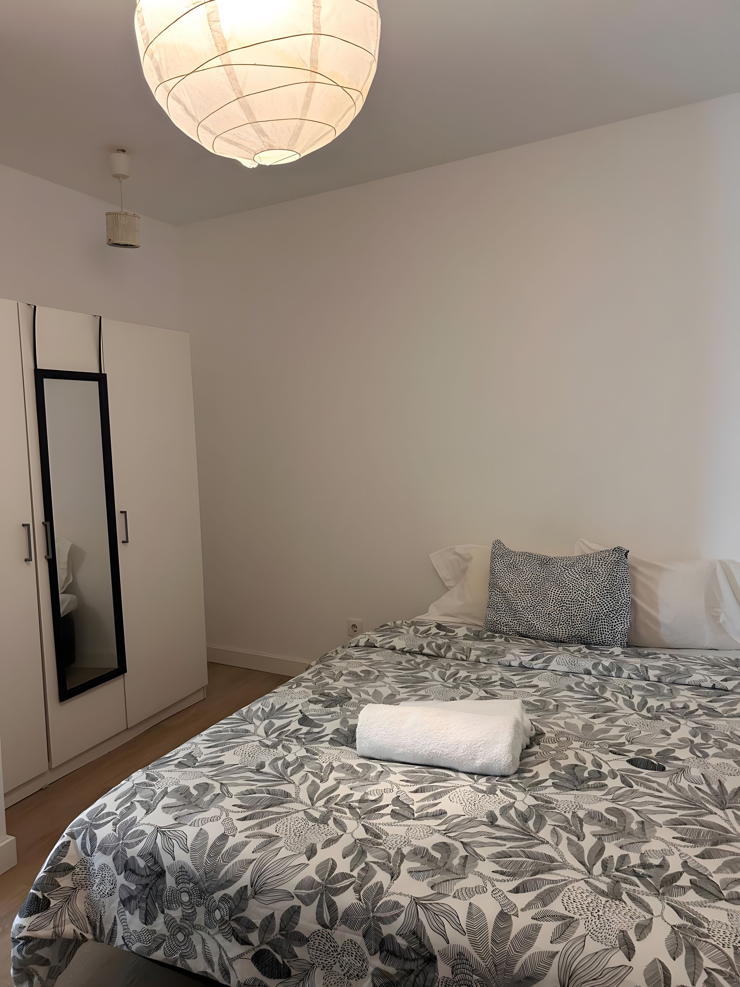 A bedroom with a bed, a wardrobe, and a hanging light fixture.
