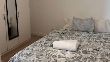 A bedroom with a bed, a wardrobe, and a hanging light fixture.