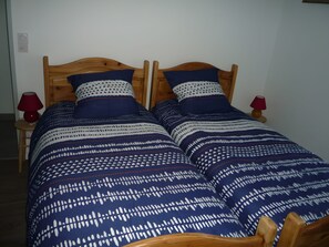 A double bed with a wooden headboard, two red lamps, and a patterned bedspread. - Holiday Home 'Les Hirondelles' (Saint-Georges-Lagricol)