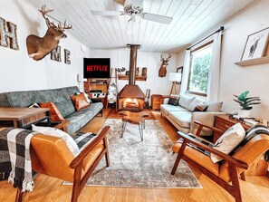 Ein gemütliches Wohnzimmer mit Kamin, einem Netflix-Schild und Hirschgeweihen an der Wand.