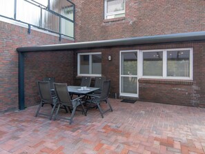 A brick building with a patio area featuring a table and chairs. - Holiday Apartment With 1 Bedroom (Esens)