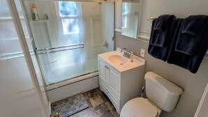 Un baño con cabina de ducha de vidrio, un lavabo blanco, un inodoro y un espejo sobre el lavabo.