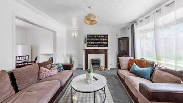 A living room with two sofas, a coffee table, a fireplace, and a bookshelf.