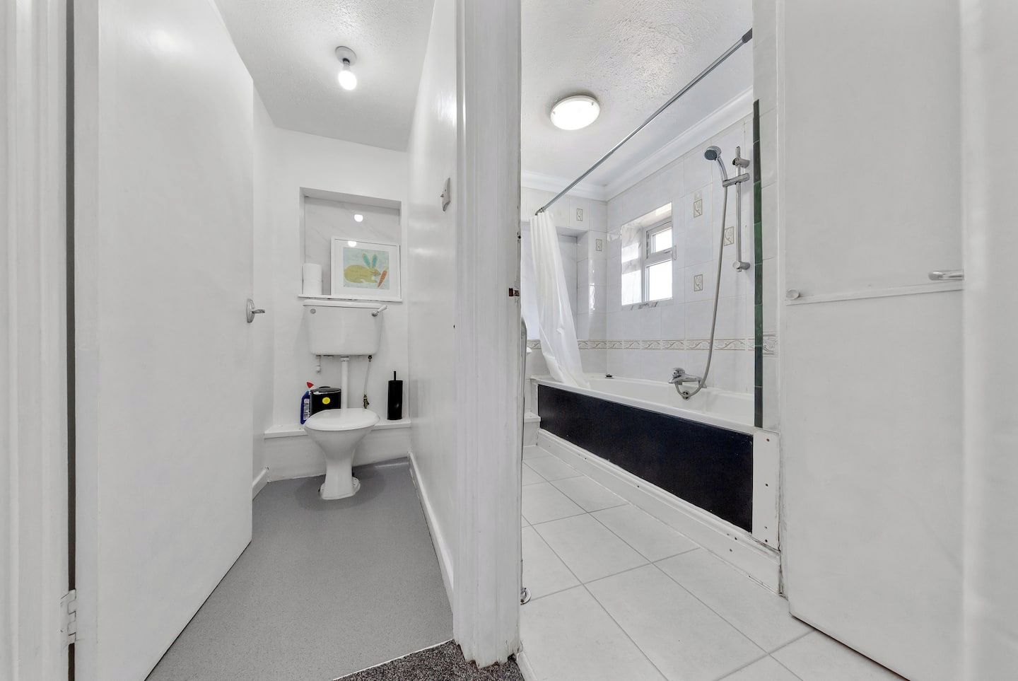 A bathroom with a toilet, a bathtub, and a shower area.