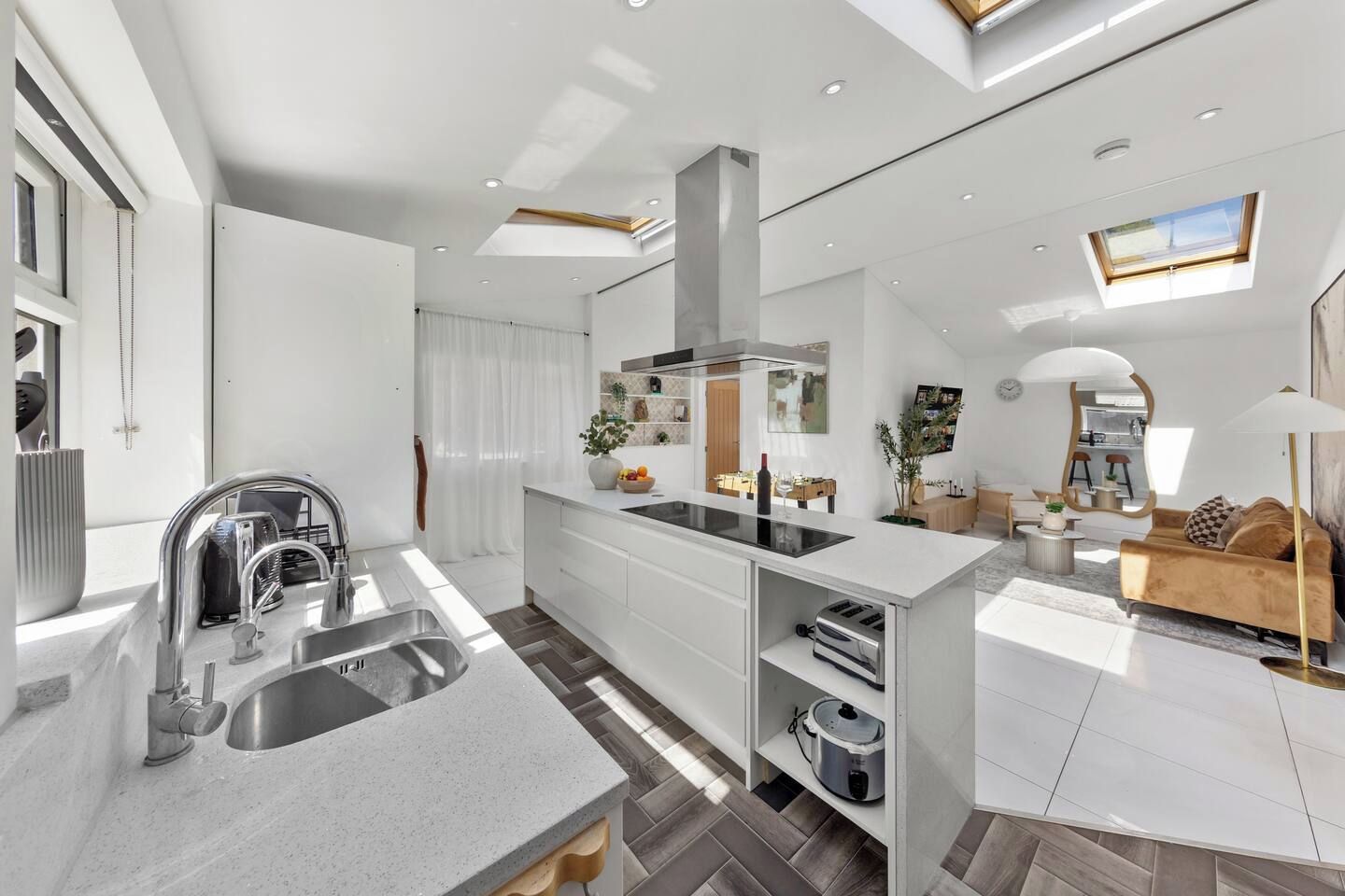 A modern kitchen with a central island, built-in appliances, and a dining area with a sofa and table.