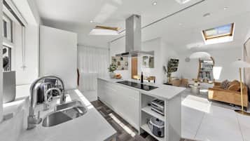 A modern kitchen with a central island, built-in appliances, and a dining area with a sofa and table.
