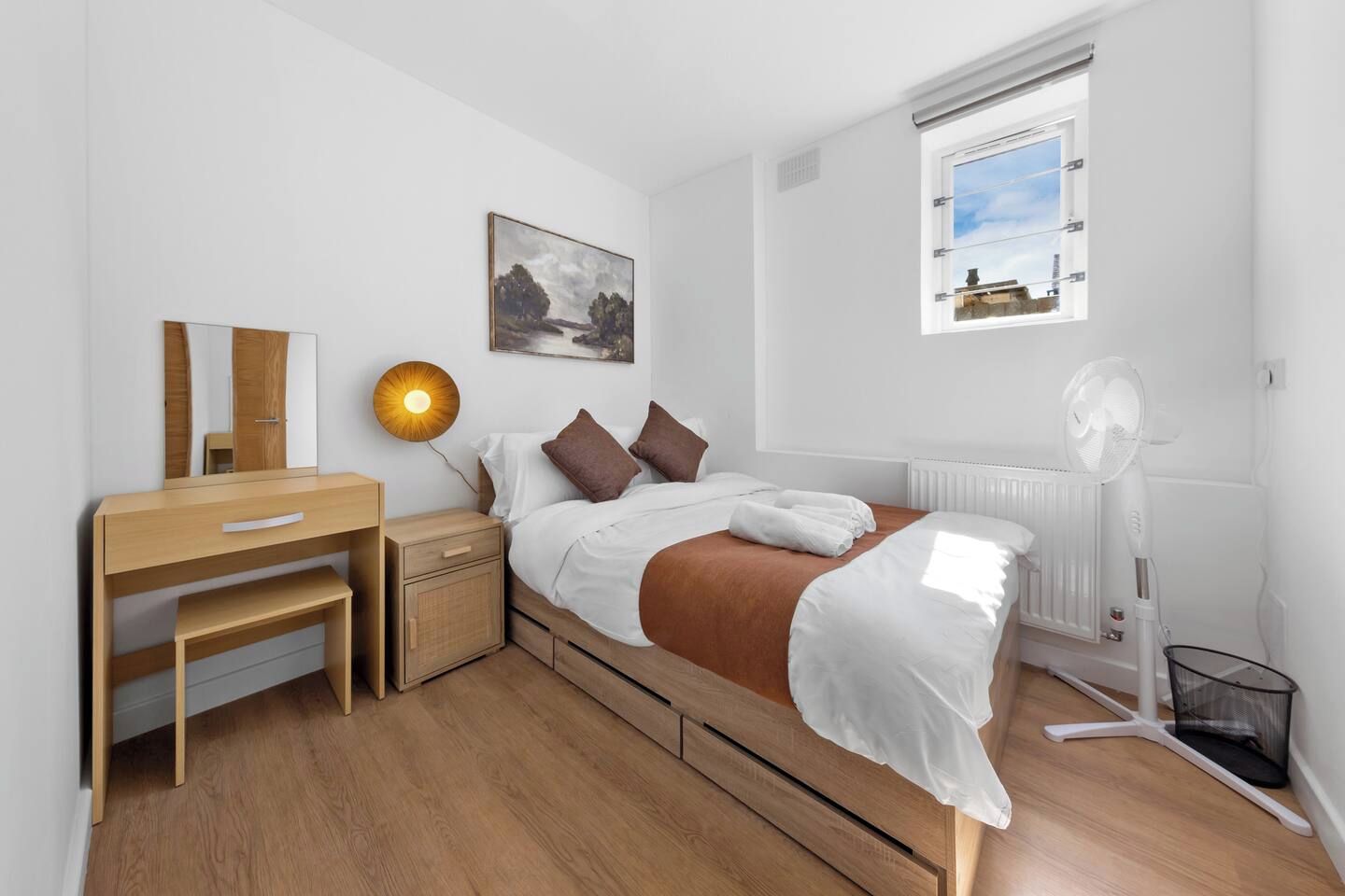 Un dormitorio con cama, mesita de noche, lámpara y ventana con vistas.