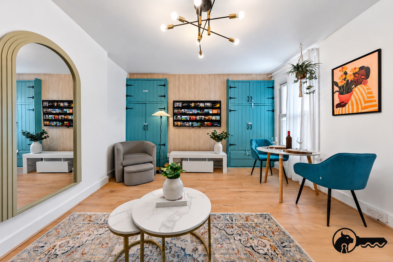 Un salon moderne avec des meubles de couleur turquoise, un fauteuil gris, une table basse ronde et une chaise bleue.