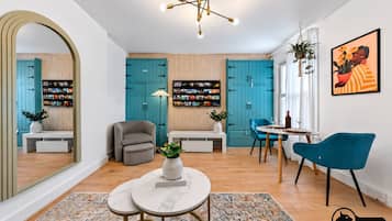 Un salon moderne avec des meubles de couleur turquoise, un fauteuil gris, une table basse ronde et une chaise bleue.