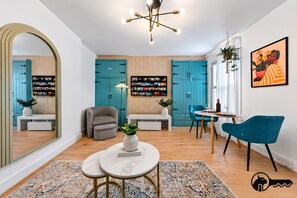 A modern living room with teal cabinets, a grey armchair, a round coffee table, and a blue chair.