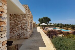 A stone building with a pool, outdoor seating, and a clear sky. - Villa Marevento by Perle di Puglia (Carovigno)