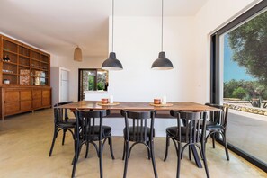 A modern dining area with a large table, black chairs, and pendant lighting. - Villa Marevento by Perle di Puglia (Carovigno)