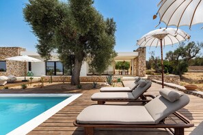 A poolside area with lounge chairs and umbrellas, surrounded by stone walls and greenery. - Villa Marevento by Perle di Puglia (Carovigno)