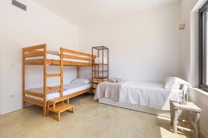 Une chambre avec un lit superposé, une petite table et une fenêtre.