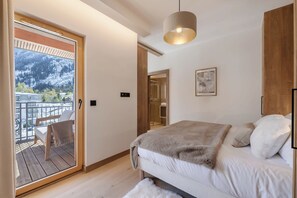 A bedroom with a bed, a wooden floor, a balcony with a chair, and a view of a snowy mountain. - Paradisa Summit - Luxurious penthouse apartment with Mont-Blanc views (Chamonix-Mont-Blanc)