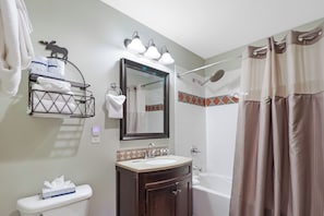 Une salle de bain équipée d’un lavabo, d’un miroir, d’un porte-serviettes, d’une douche et de toilettes.