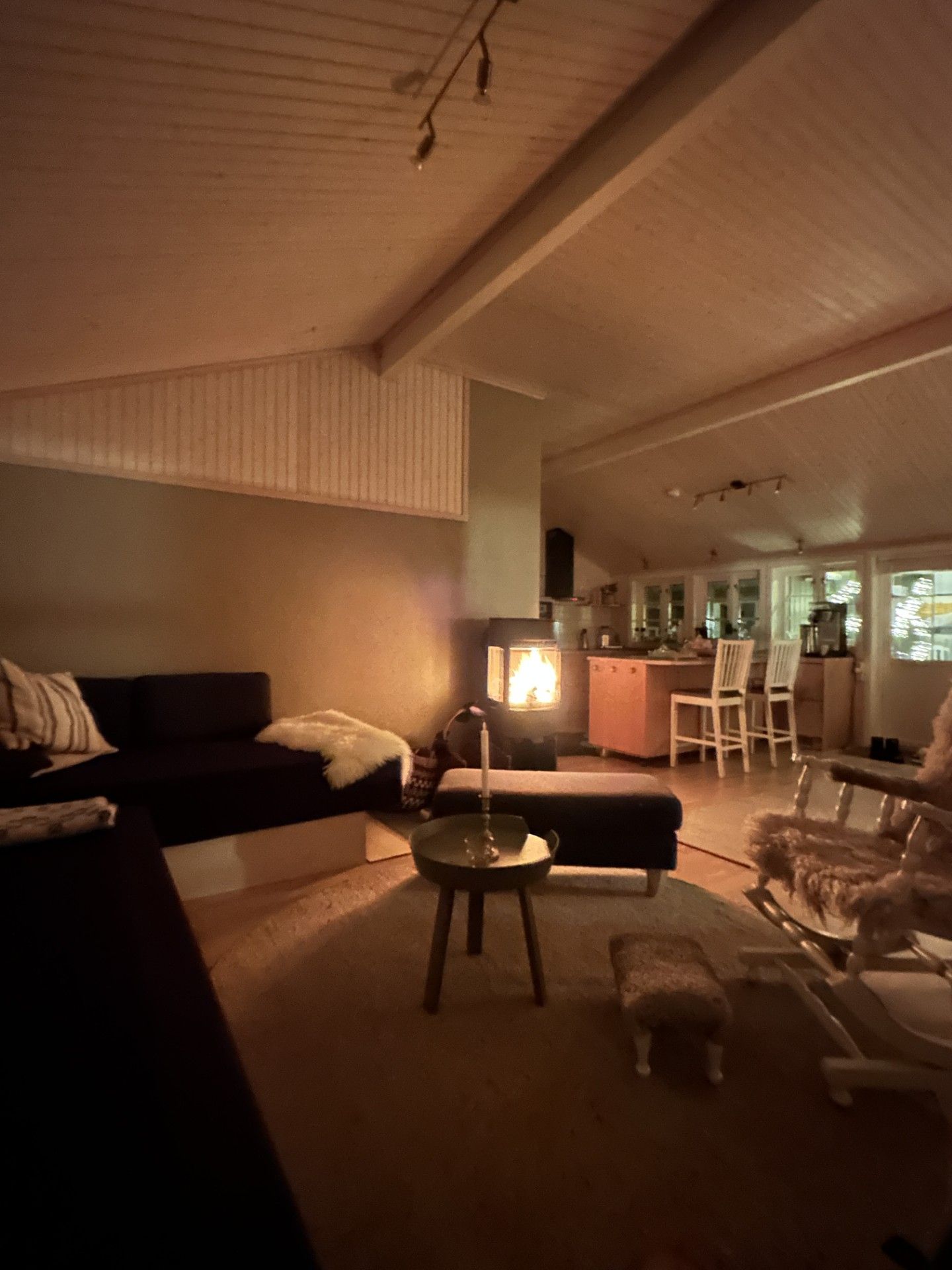 Un salon chaleureux avec une cheminée, un canapé, une table basse et un coin repas avec des chaises.