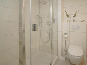 Ein Badezimmer mit einer Duschkabine, einer Toilette und einem Handtuchhalter mit Vogelmotiven.