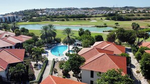A residential area with a swimming pool surrounded by houses with red-tiled roofs. - Penthouse Villa steps from Blue Bay Beach (Sint Michiel)