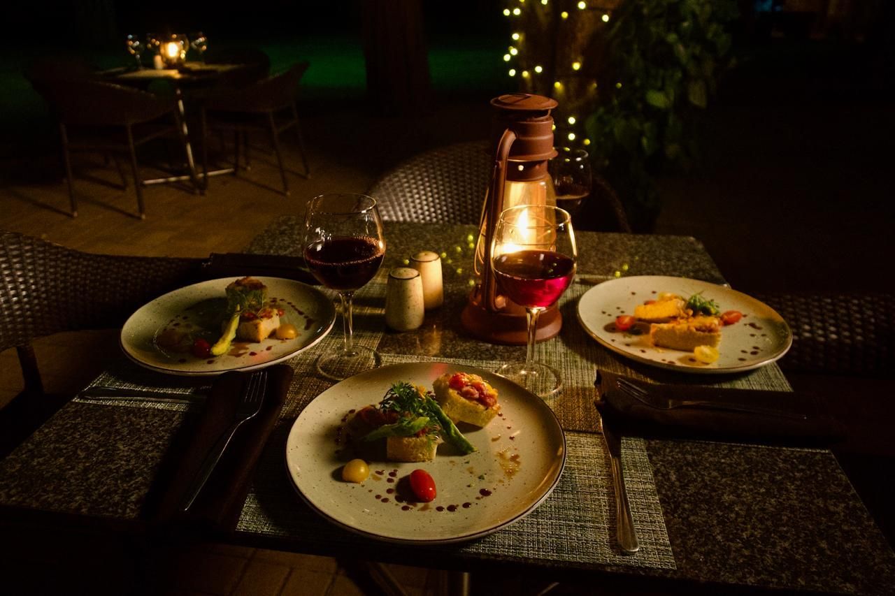 Mesa posta para refeição, com pratos de comida, copos de vinho e uma vela.