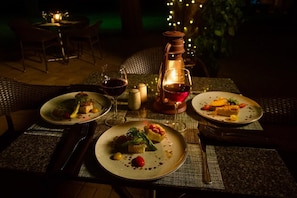 Una mesa lista para una comida, con platos de comida, copas de vino y una vela.