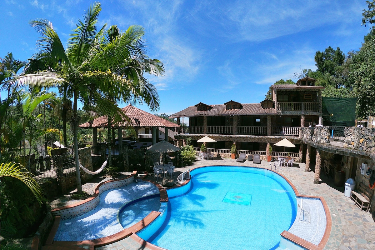 A resort with a swimming pool, outdoor seating, and a multi-story building.