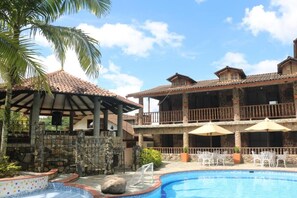Hotel com piscina, área de estar externa e varanda coberta.