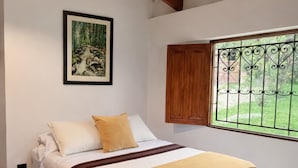 A bedroom with a bed, a window with a view, a ceiling fan, and a framed picture on the wall. - La Casa del Arbol (San Francisco)