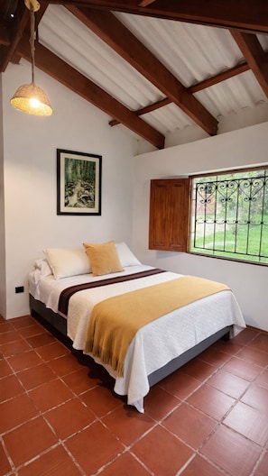 A bedroom with a bed, a window with a view, a ceiling fan, and a framed picture on the wall. - La Casa del Arbol (San Francisco)