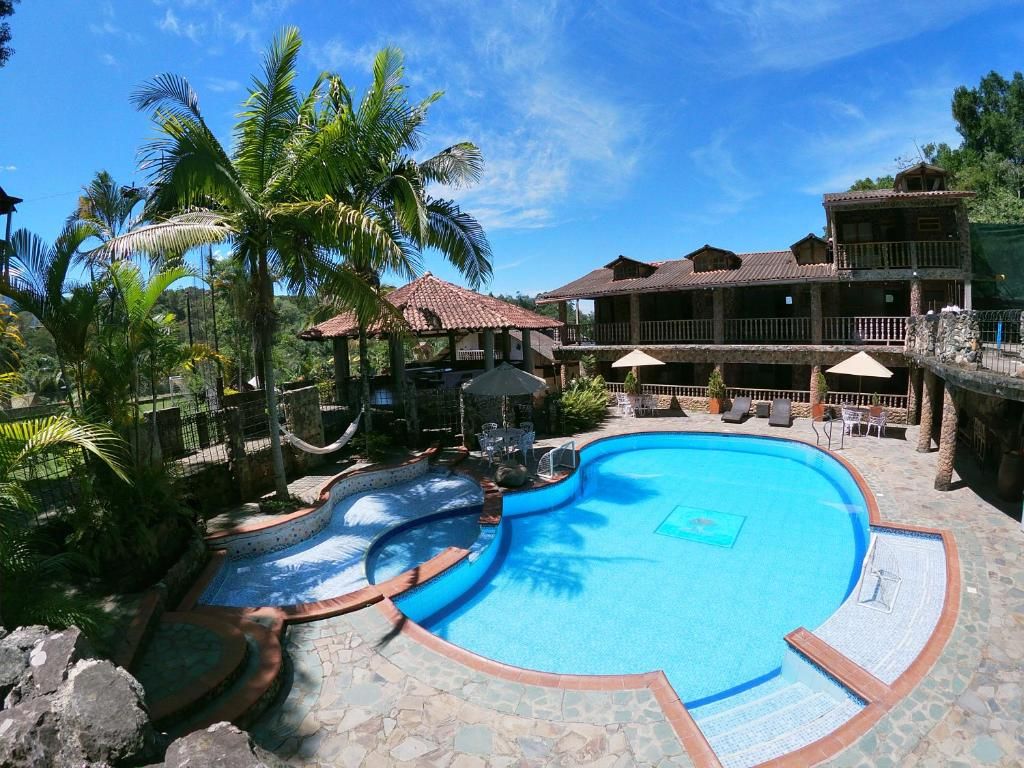 Ein Resort mit großem Schwimmbad, Palmen und einem Gebäude mit Balkonen.