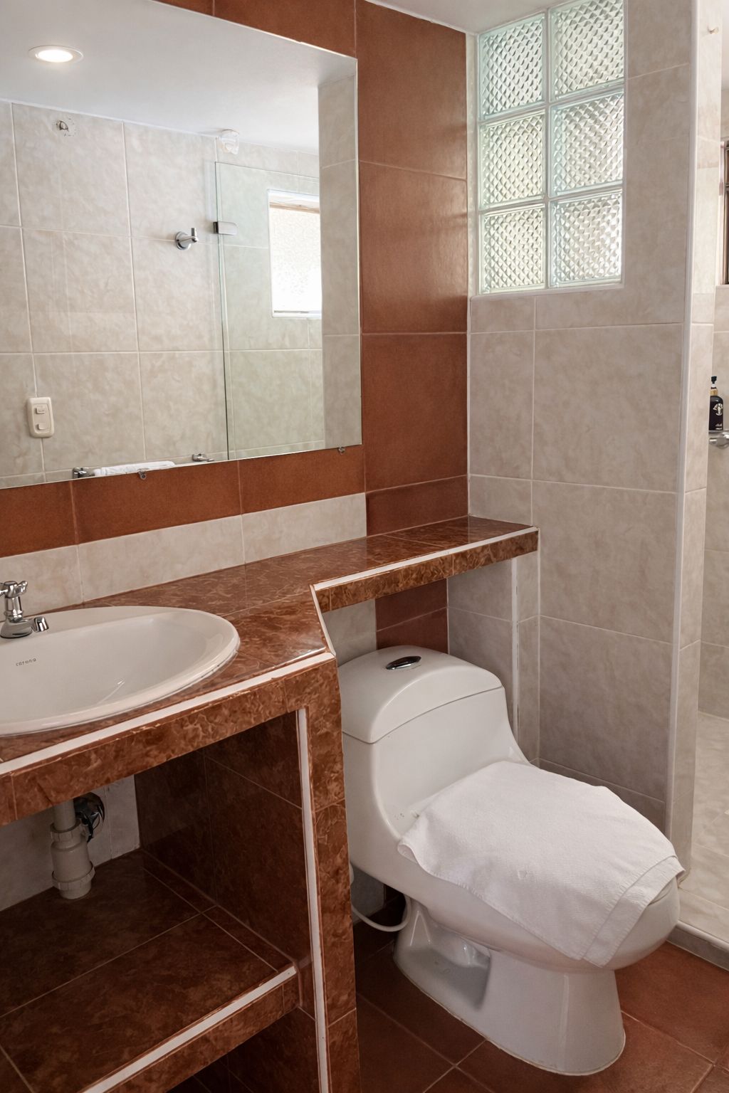 Un baño con lavamanos blanco, inodoro y espejo.