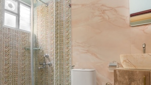 A bathroom with a glass shower enclosure, a toilet, and a vanity with a sink. - Casa Albela (Bengaluru)
