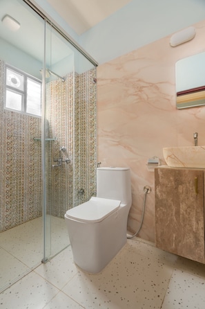 Een badkamer met een douchecabine van glas, een toilet en een wastafelmeubel met een wastafel.