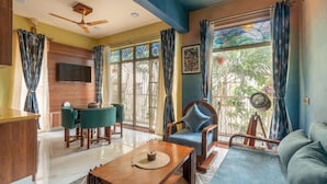 A living room with a sofa, a coffee table, a TV, and a dining area with chairs and a table. - Casa Albela (Bengaluru)