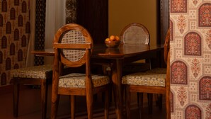 A dining area with a wooden table, chairs, a ceiling fan, and patterned wallpaper. - Casa Albela (Bengaluru)