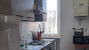Een keuken met een ingebouwde kookplaat, oven en magnetron. Er is een raam met uitzicht op het omliggende landschap.