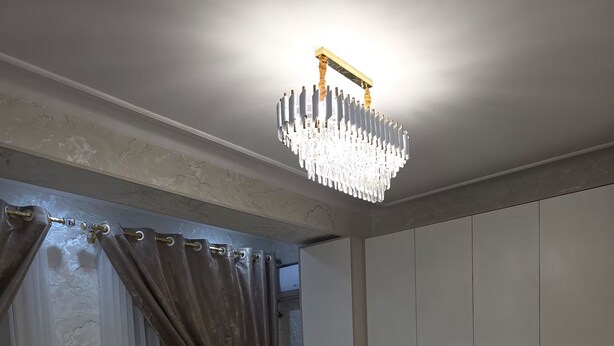 Een slaapkamer met een groot bed, een kroonluchter, een kledingkast en een raam met gordijnen.