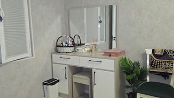 Ein Schlafzimmer mit einem Bett, einem Schreibtisch, einem Stuhl, einem Spiegel, einem Fenster mit Jalousien, einer Mülleimer und einer Zimmerpflanze.