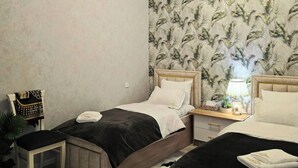 Een moderne slaapkamer met twee bedden, een nachtkastje, een lamp en een decoratieve wand.