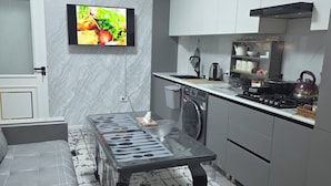 Een moderne keuken met een ingebouwde oven, een magnetron en een waterkoker op het aanrecht.